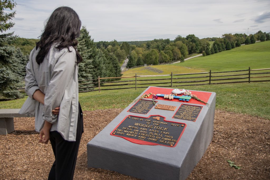 A woman looks onto a plaque commemorating the original Woodstock location in Bethel, New York.