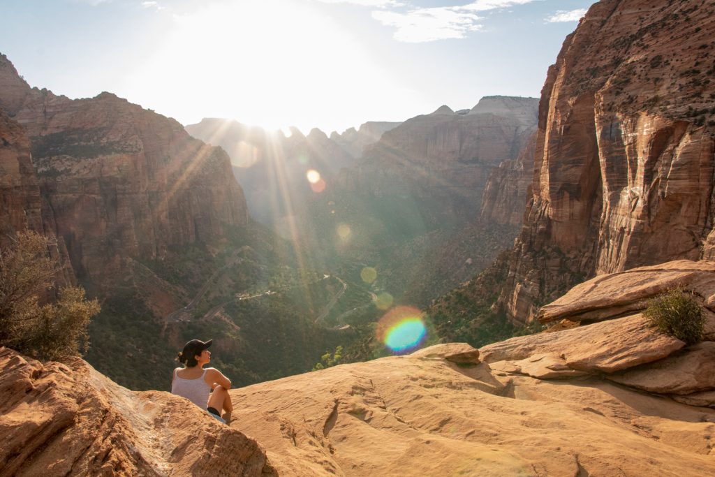 A woman sits near a ledge that overlooks a valley at Zion National Park in Utah.