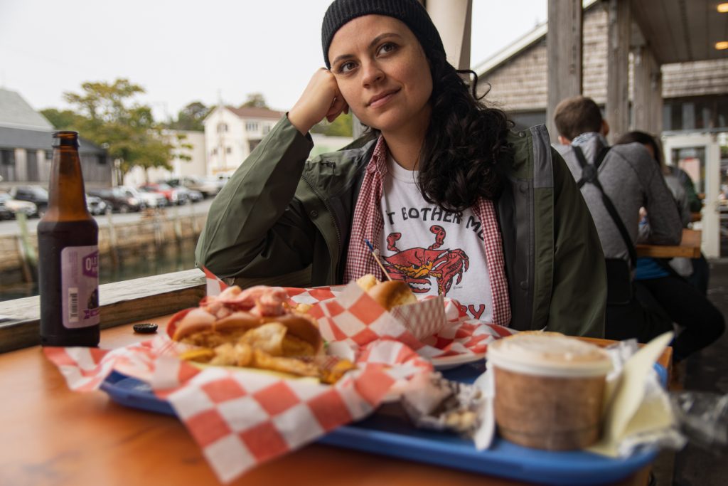 A woman eating Lobster rolls and chowder at Beal's Lobster Pier near Acadia National Park in Maine.