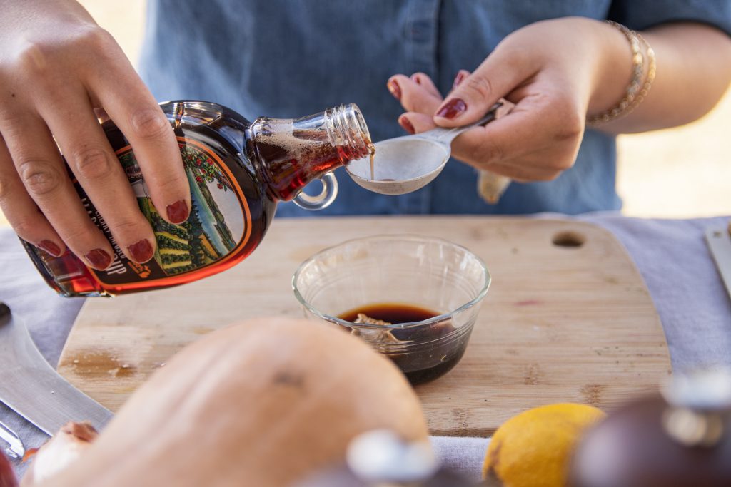 A person pours Cherry Republic's Cherry-infused Maple syrup into a measuring tablespoon.