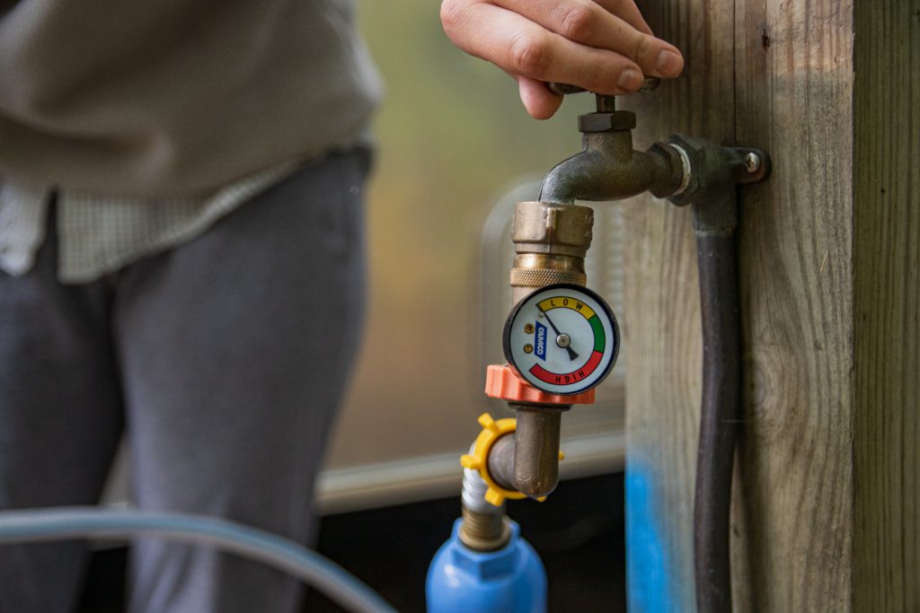 A person turns the water connection that leads to a water pressure regulator. 