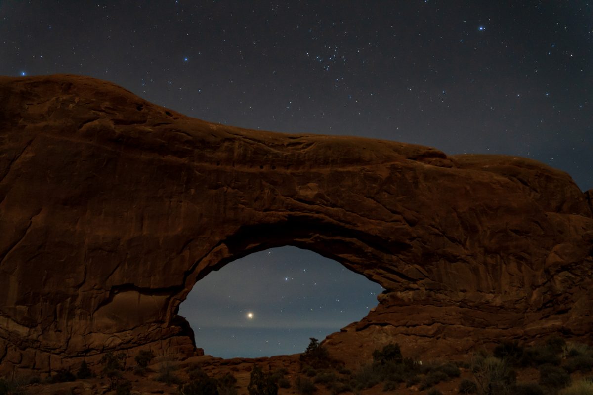 The North Window Arch is seen at night with stars shining behind it at Arches National Park in Moab, Utah.