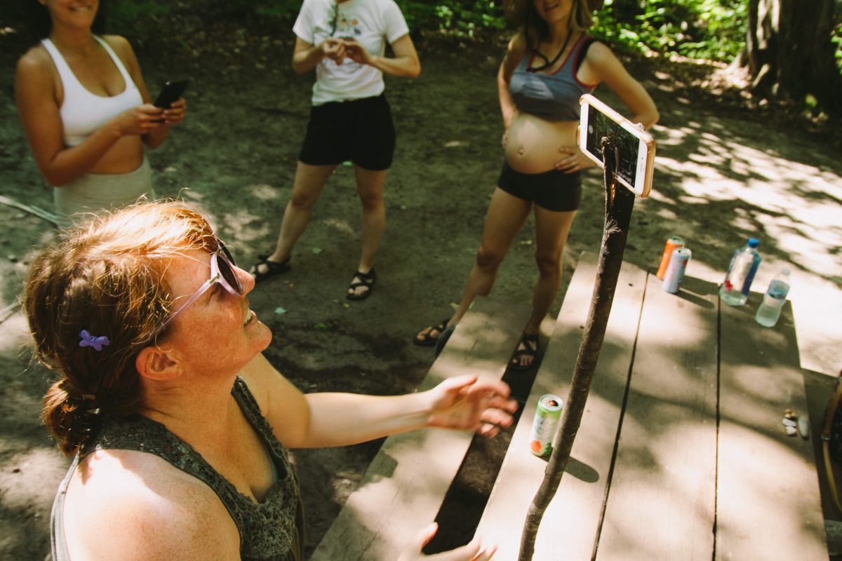 A woman holds up her phone with an actual wooden stick at a campsite at Fisherman's Island State Park in Northern Michigan.