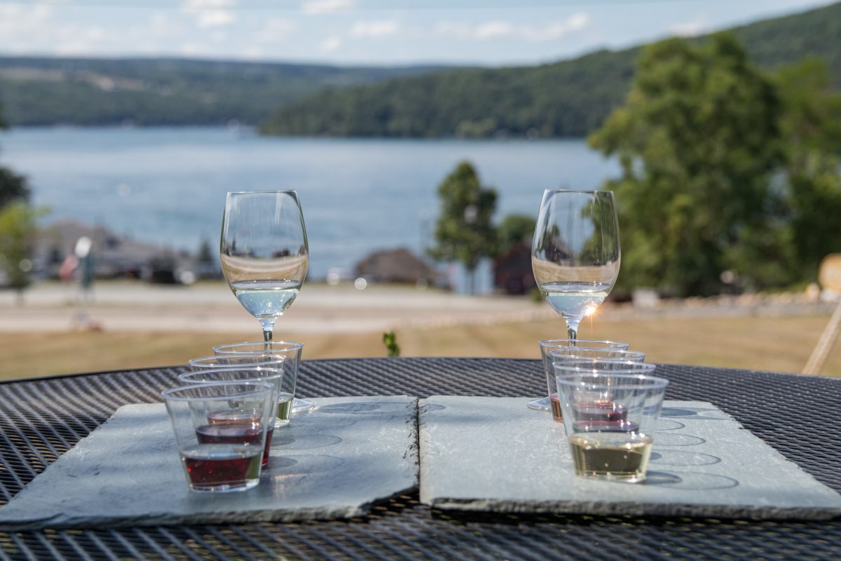 A wine tasting flight sits on top of a table looking out to Keuka Lake at Ravines Wine Cellars in Hammondsport, NY.