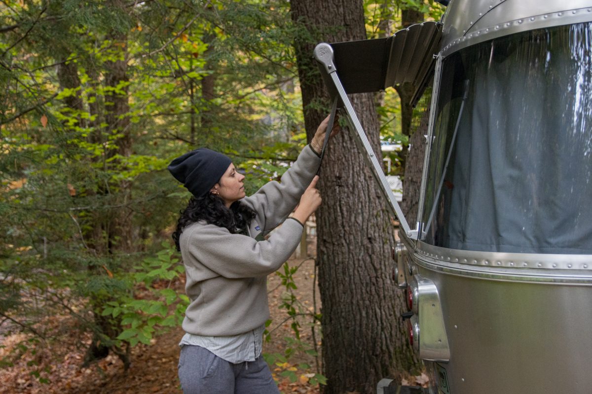 A woman pulls out the awning on her Airstream trailer.