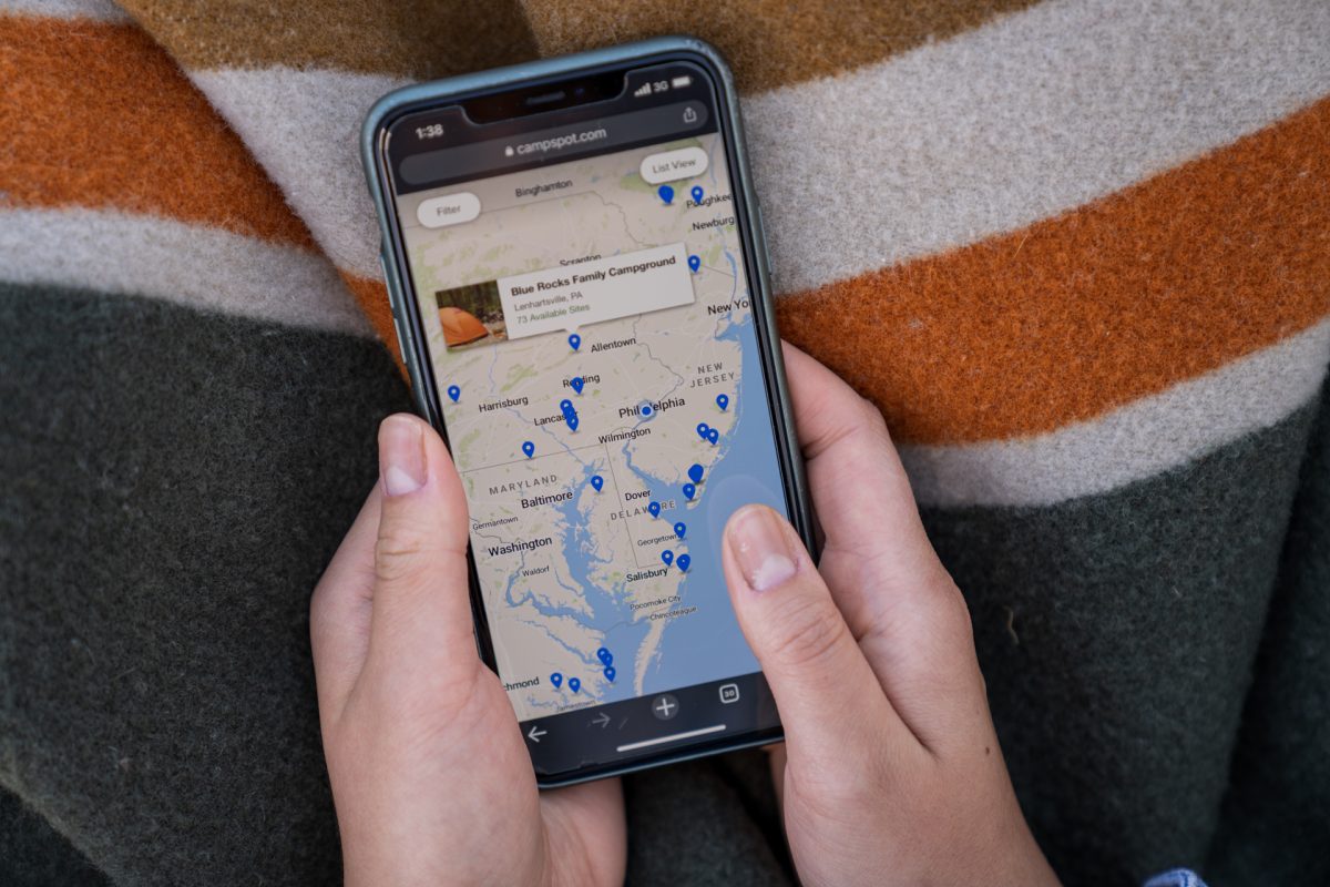 A person scrolls through campground listings on Campspot on their phone.