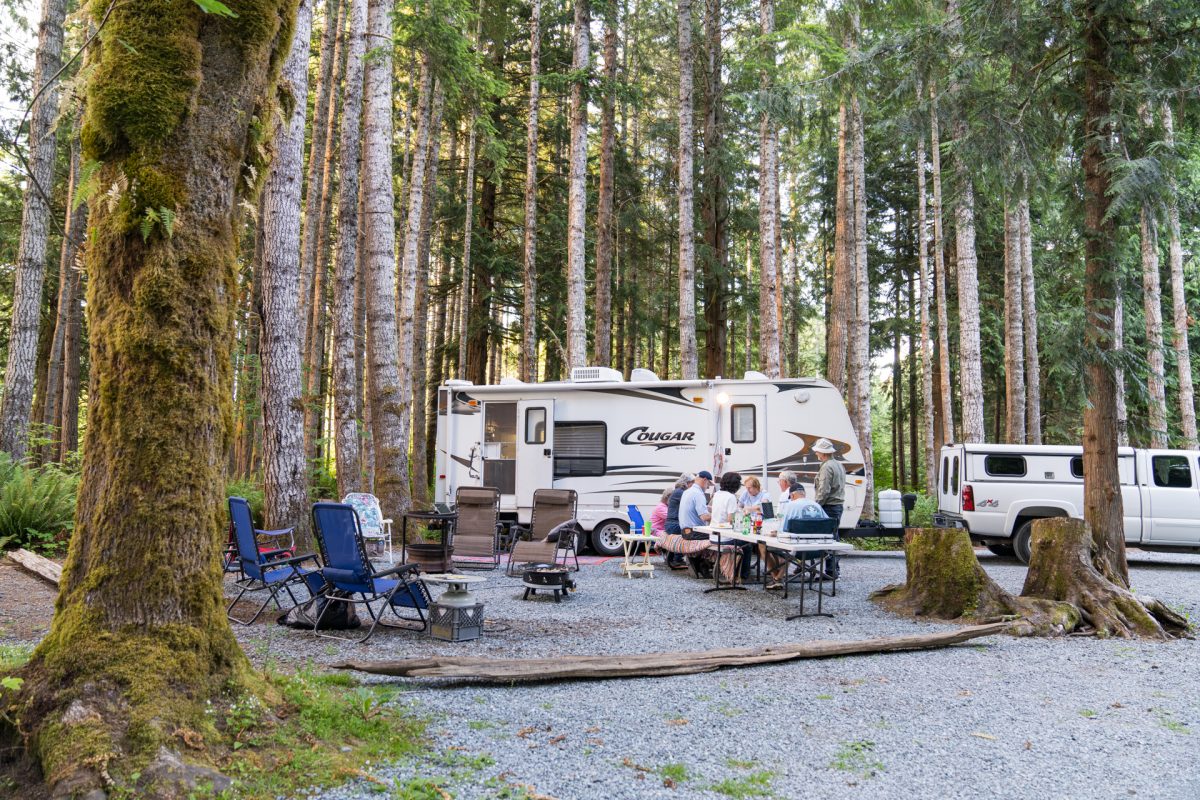 A group of friends play cards in front of their RV at their campsite at Elkamp Eastcreek Campground in Mineral, Washington.
