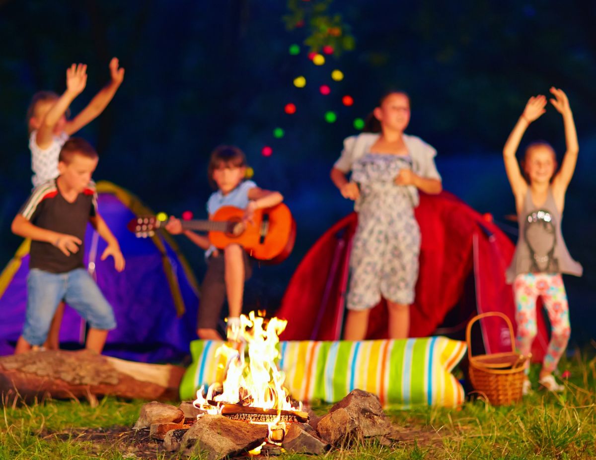 Kids singing around the campfire with guitar 
