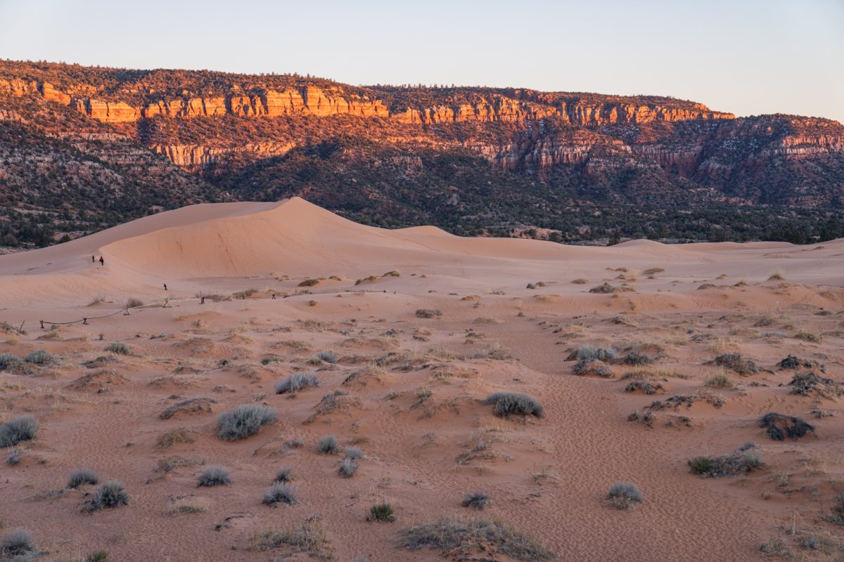 The sun setting against the cliffs behind the dunes at Coral Pink Sand Dunes State Park located just outside of Kanab, Utah.