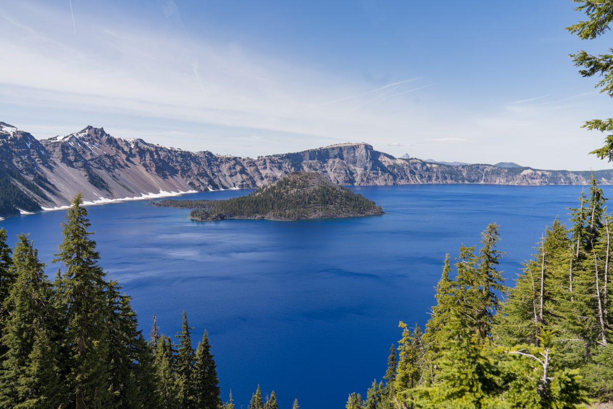Crater Lake National Park with Wizard Island on a sunny day. Crater Lake National Park is a must-visit stop on an Oregon road trip.