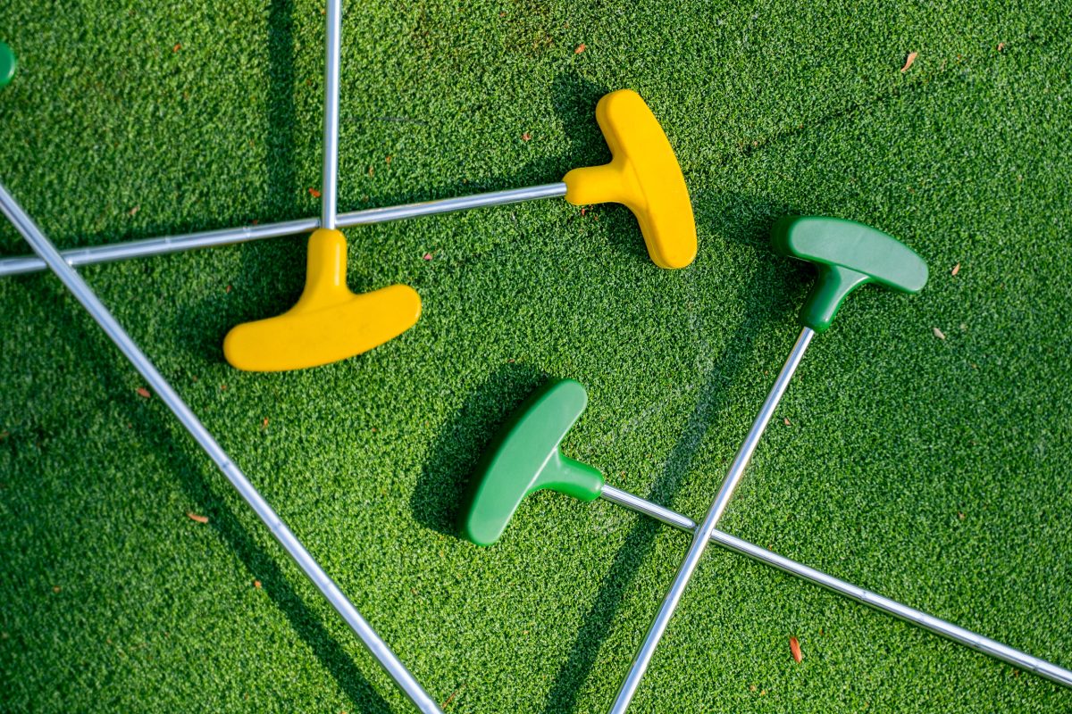 Mini golf putters on top of green turf. 
