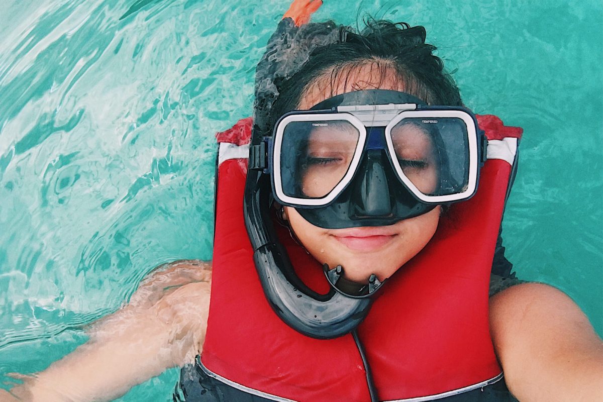 A person floats on their back with snorkel gear on. 