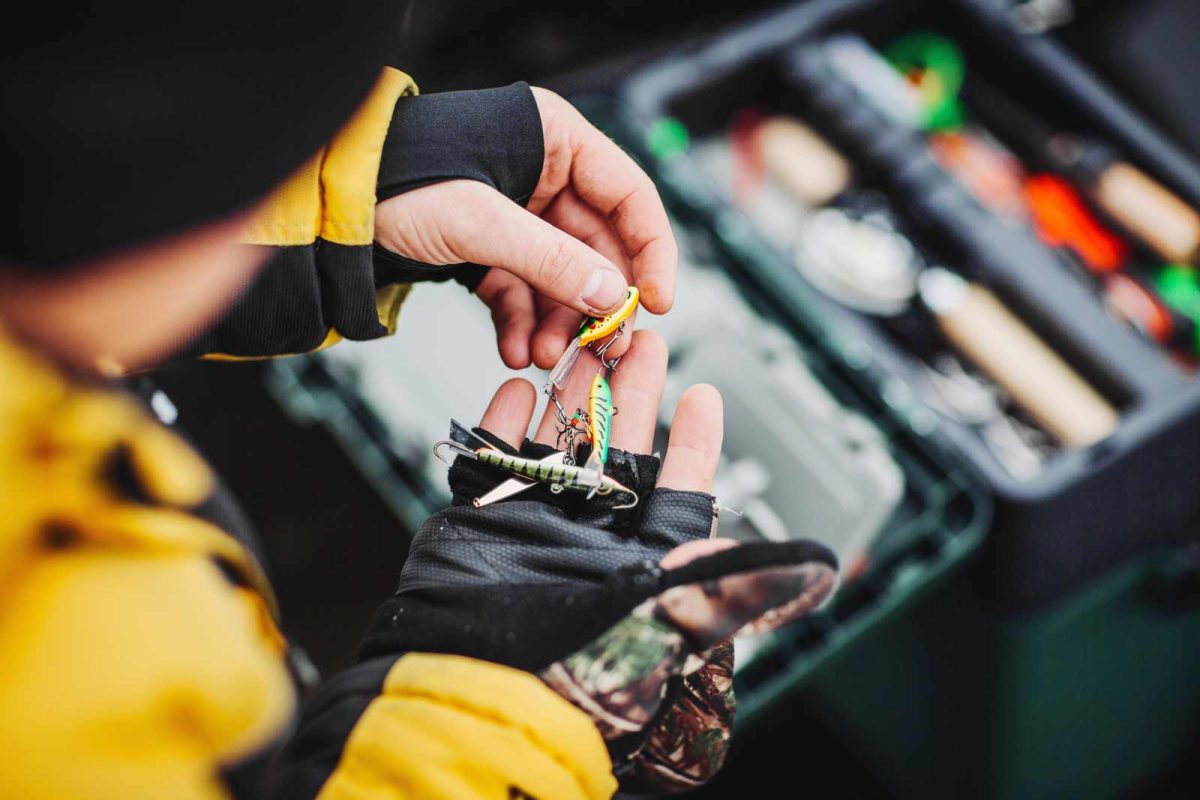 Fishing lures in hands over a tackle box