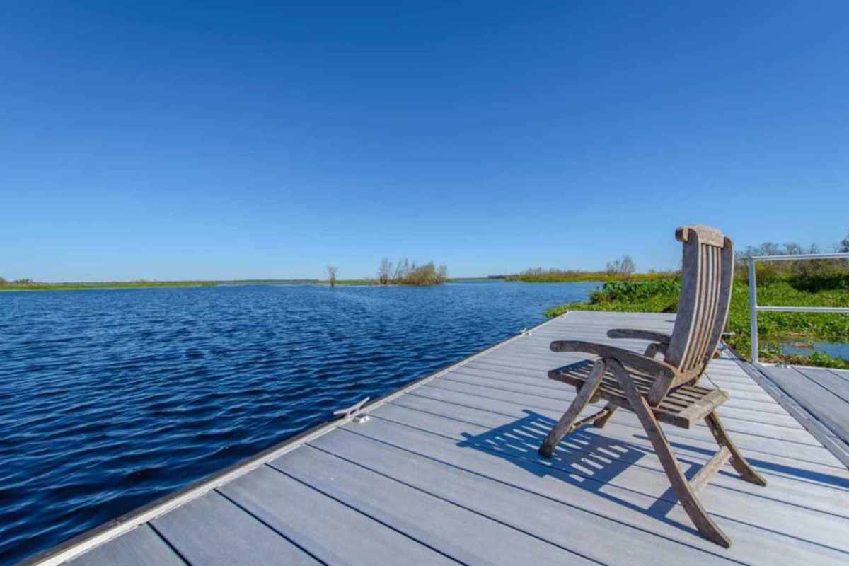 An empty chair sits on a dock overlooking the water. 