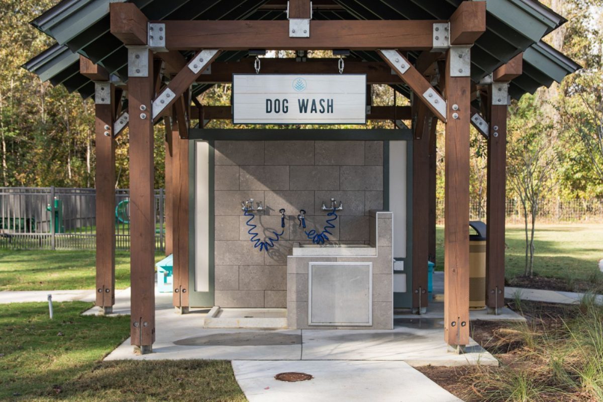A pavilion with a dog wash station with hoses and a sign above that says "dog wash" at Carolina Pines RV Resort, a pet-friendly campground. 