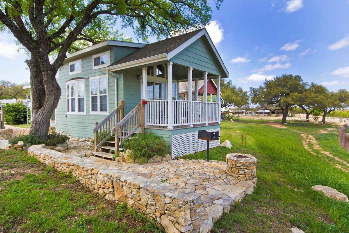 A mint-colored cabin with a stone patio at Sun Outdoors Lake Travis. 