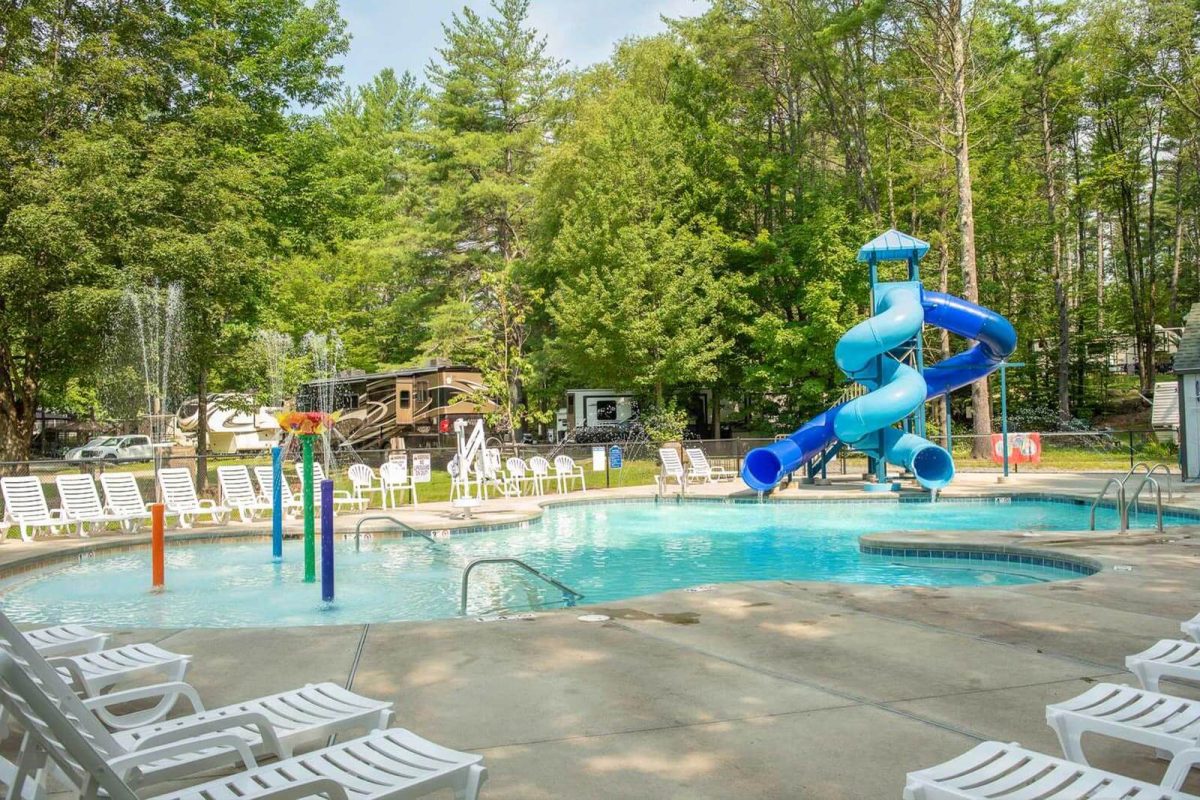 Two water slides empty into a pool with spraying water features at Spacious Skies Seven Maples Campground. 