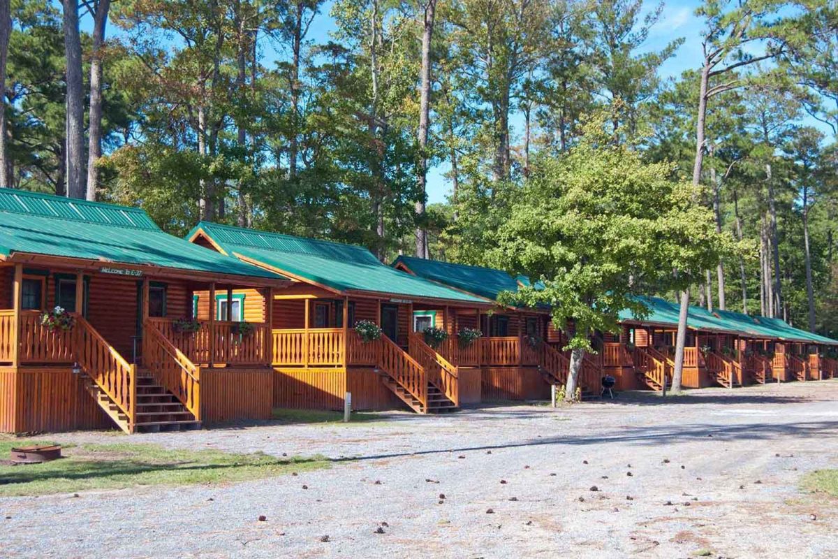 A row of cabins under trees at Sun Outdoors Frontier Town, a popular Assateague Island camping destination 