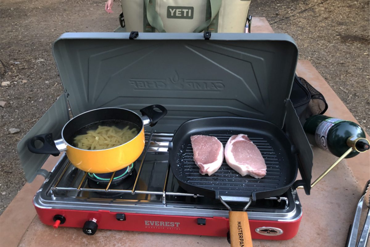 Two pans of food cooking on a camping grill stove - one of our camping gift ideas for 2022 