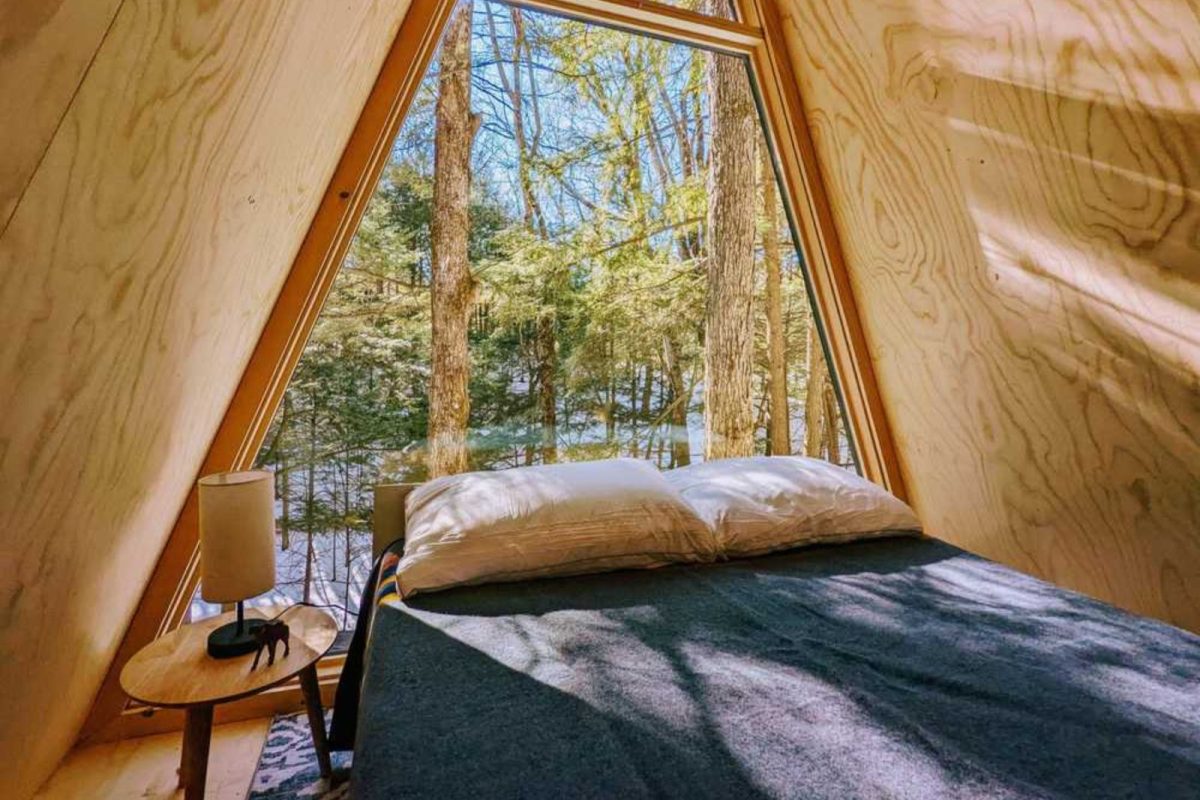 bedroom at A-frame cabin with trees outside glass window