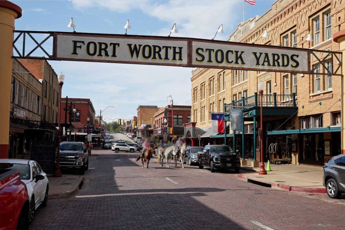 Fort Worth Stock Yards sign with two people riding horses down the street