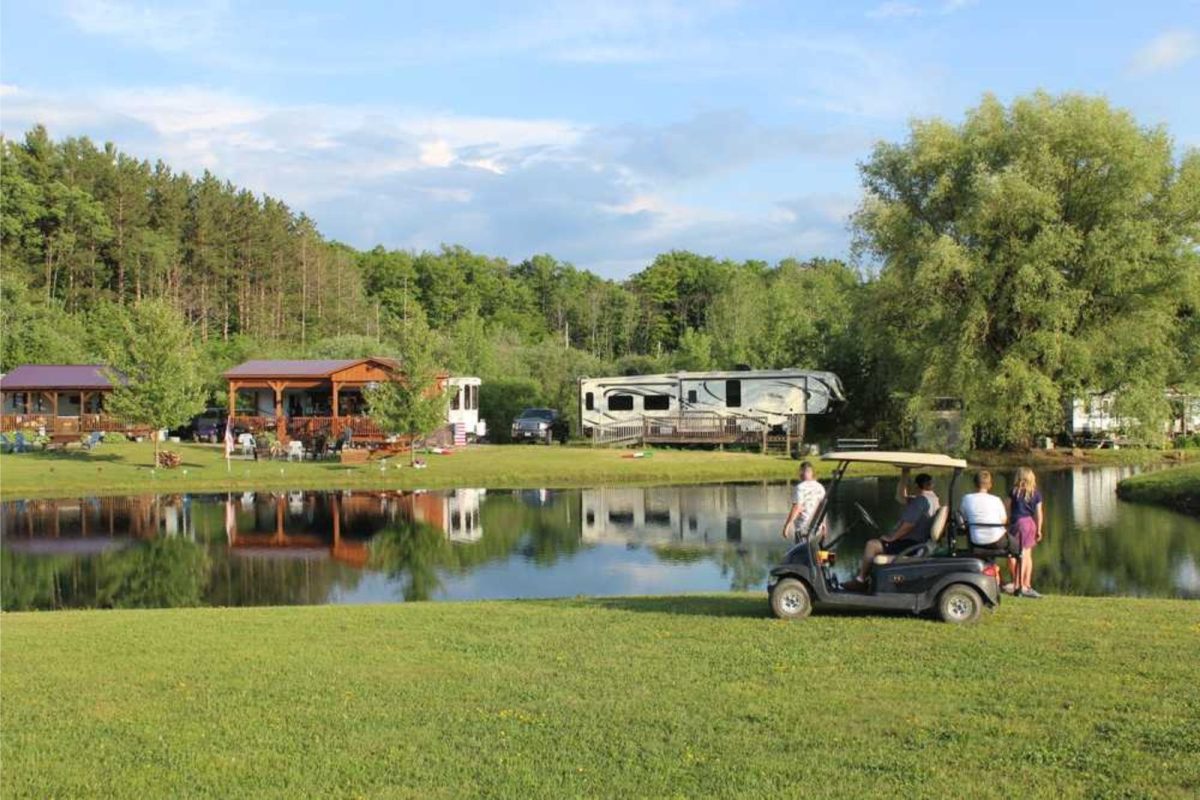 golf cart and family parked by lake inside campground near Rochester, NY