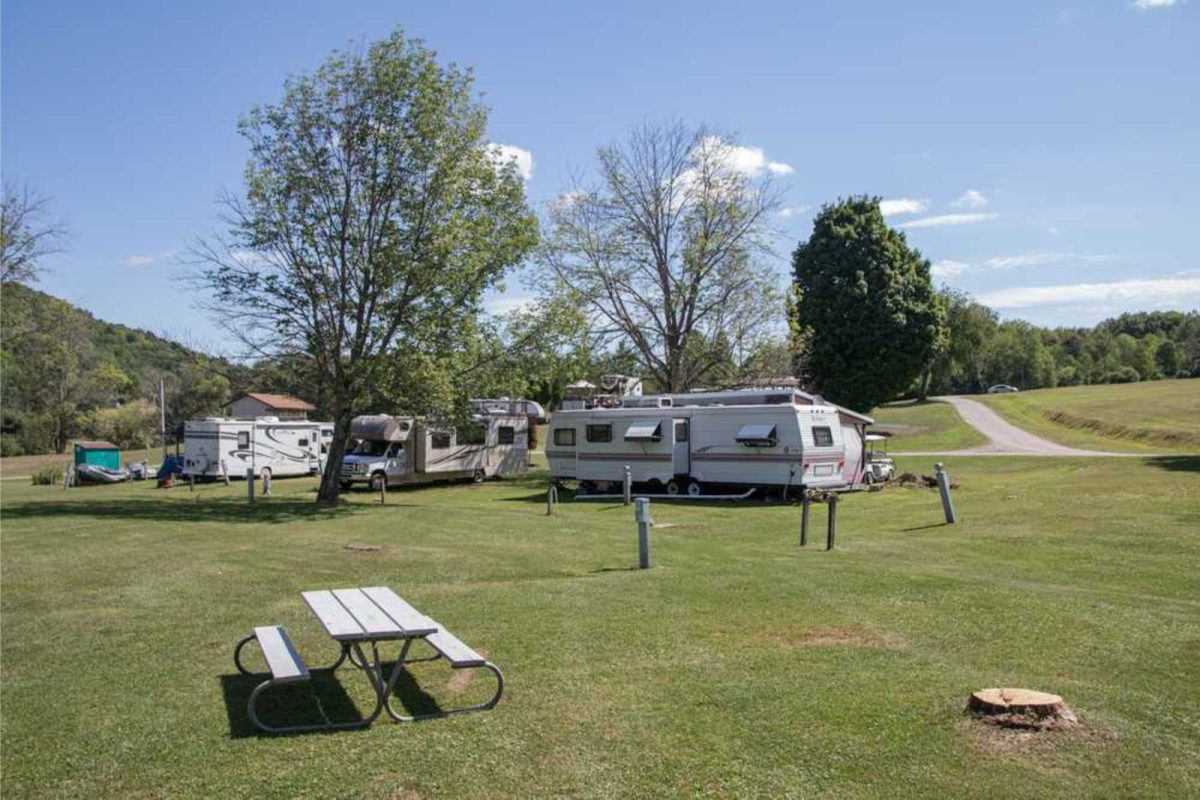 RVs parked on grassy field with picnic bench at campground near Rochester, New York