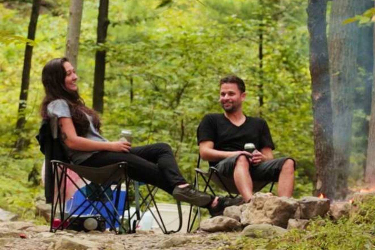 couple sitting on camping chairs in woods