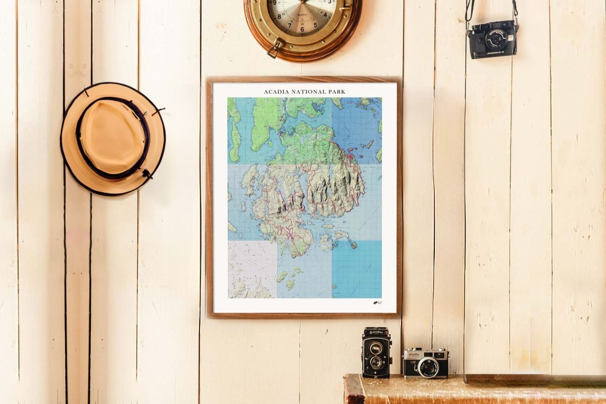 A relief map of Acadia National Park framed on a plank wall with a hat, clock, and camera hanging nearby. 
