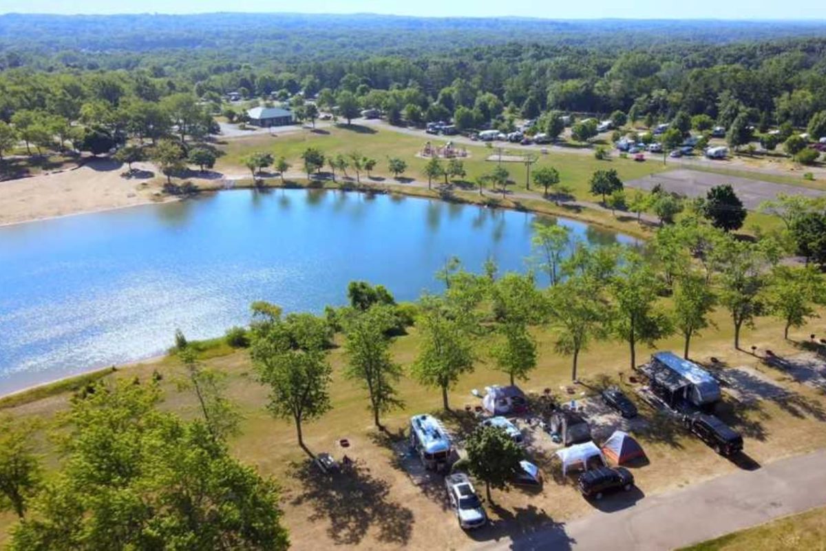 aerial view of Camp Dearborn campground, with RVs, trailers, and tents around a shimmering lake