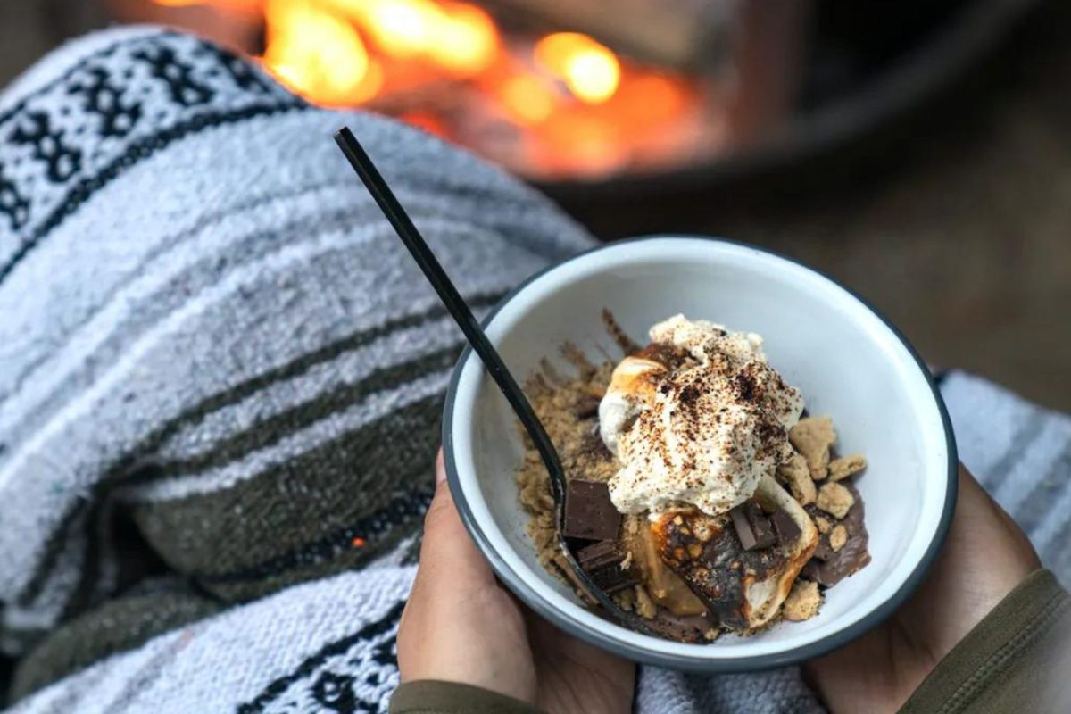 camper holding a bowl of a s'more sundae (creative, easy camping recipe) by the campfire