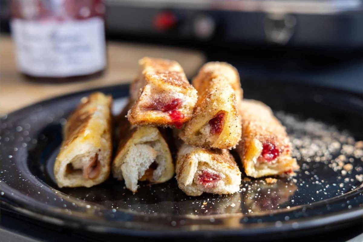 plate full of French toast roll-ups with jam and cream cheese