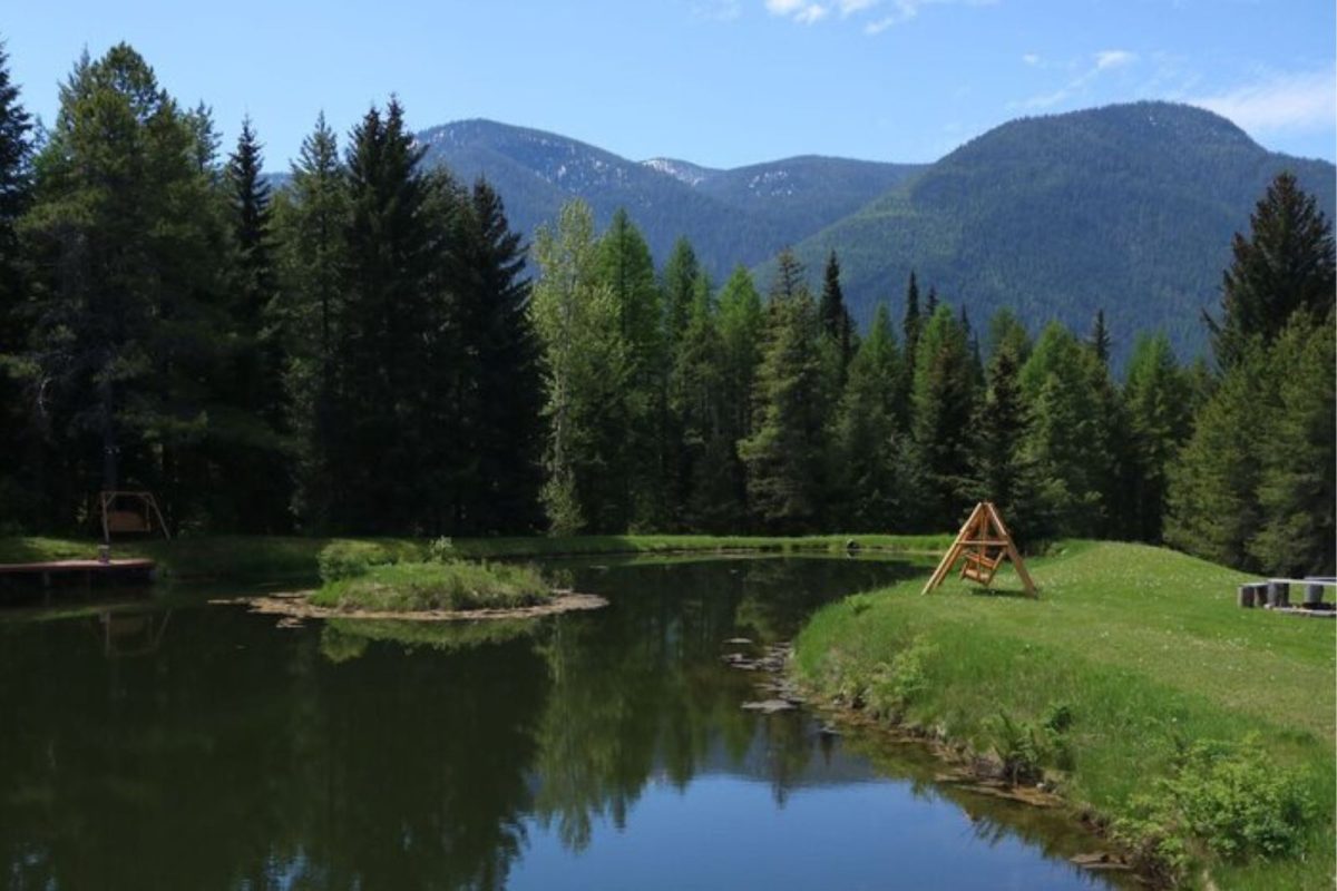 swinging bench by peaceful lake at Meadow RV Park & Cabins near trending national park Glacier National Park