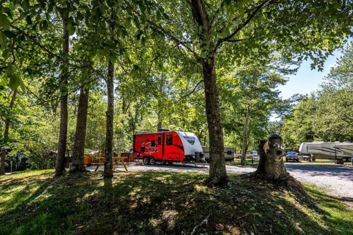 red trailer and RVs parked under trees at campground